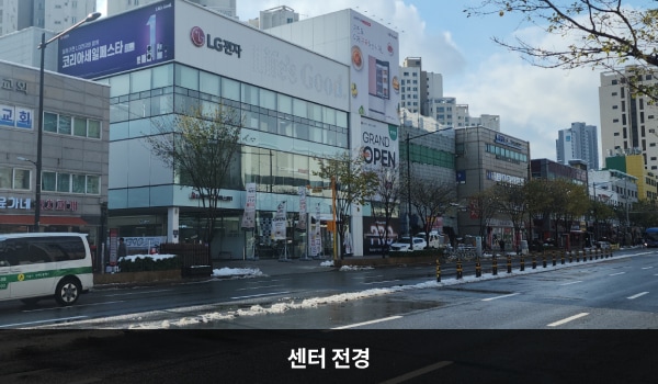 양천서비스센터의 서비스센터 건물은 오른쪽 부분만 타워형으로 높이가 더 높은 특징이 있습니다. 벽면에 큰 창문이 많습니다. 건물 위 간판에 흰색 바탕으로 'LG전자 Life's Good' 문구가 쓰여 있습니다.