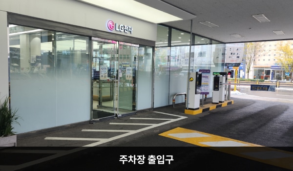 양천서비스센터의 건물 왼쪽 끝에 지상 주차장 출입구가 있습니다. 주차장 입구 위에 작은 'LG전자 서비스센터' 간판이 있습니다. 건물 뒤에서도 주차장을 통해 들어갈 수 있는 자동문 출입구가 있습니다.