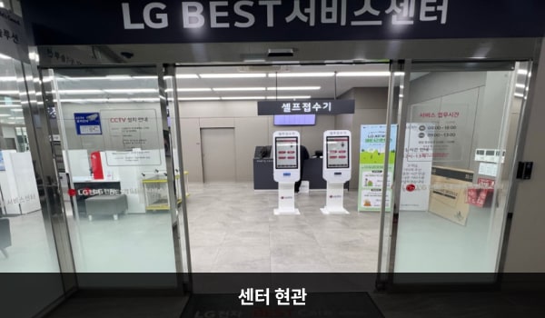 강서서비스센터의 센터 현관 위쪽에 'LG BEST 서비스센터'라는 문구가 적혀 있으며, 그 아래에 자동문이 있습니다. 문을 열고 들어가면 앞에 셀프 접수기가 있습니다.