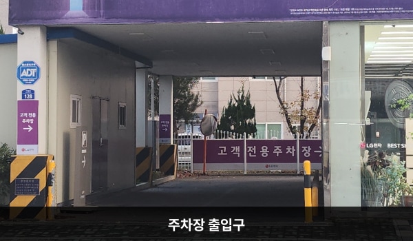 거창서비스센터의 건물 왼쪽 끝에 주차장 출입구가 있습니다. '고객전용주차장' 안내문이 왼쪽 벽면과 정면에 붙어 있습니다.