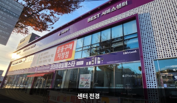 의왕서비스센터의 서비스센터 건물은 가로로 길고 유리창이 많습니다. 건물 위쪽 간판에 흰색 글씨, 분홍색 바탕으로 'LG전자 BEST SHOP 베스트샵', 'BEST 서비스센터'라고 쓰여 있습니다.