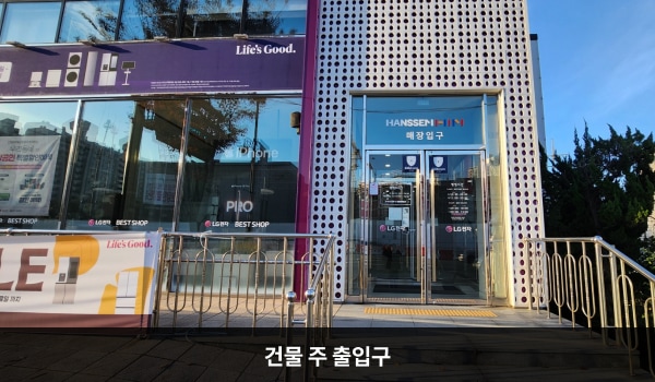 의왕서비스센터의 대로 앞에서 건물을 바라봤을 때 오른쪽 끝에 여닫이문으로 된 서비스센터 출입구가 있습니다. 진입할 때 옆에 철 손잡이가 있는 5칸 계단이 있으며, 출입구 앞에 점자블록이 있습니다. 건물 중앙 여닫이문 출입구는 베스트샵 입구입니다.