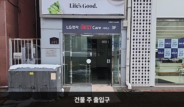 부천서비스센터의 건물 주 출입구 위에는 'LG BEST Care 서비스 3F'라는 문구가 적혀 있습니다. 출입문 앞에 경사진 턱이 있으며, 양쪽 유리문 안쪽에 동그란 손잡이가 있습니다.