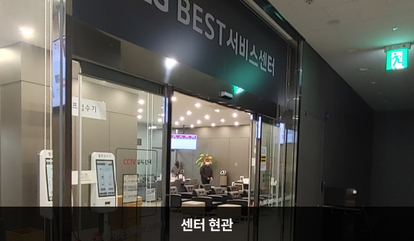 남수원서비스센터의 4층 현관문 위쪽 큰 회색 간판에 'LG BEST 서비스센터'라고 적혀 있습니다. 현관문은 자동문이고, 문 왼쪽에 열림 버튼이 있습니다. 들어오시면 정면에 셀프 접수기가 있습니다.