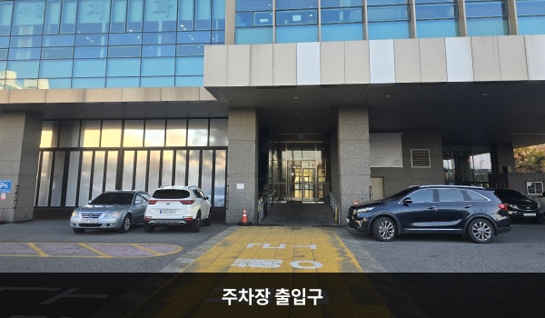 서대전서비스센터의 출입구에서 건물을 크게 돌아 건물 뒤편으로 가면, 지하 주차장으로 들어갈 수 있는 입구가 있습니다. 왼쪽 가로등 위 노란 안내문에 '주차장입구'라고 쓰여 있습니다.