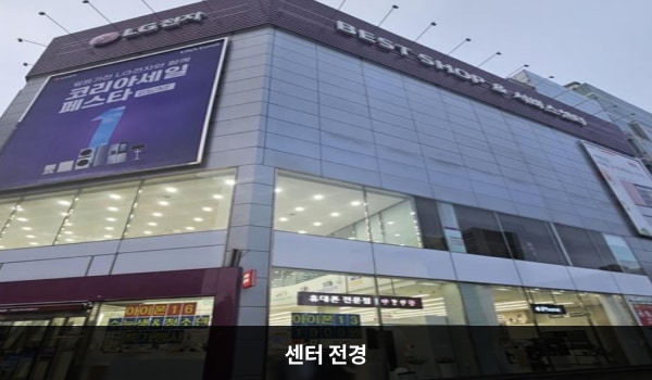 둔산서비스센터의 흰색 건물 맨 위층을 둘러싼 붉은 간판에 'LG전자', 'BEST SHOP & 서비스센터'라고 쓰여 있습니다. 건물의 1층과 2층에는 유리창이 크고 많습니다.