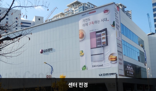 서면서비스센터의 서비스센터 건물은 높고 흰색이며 창문이 보이지 않습니다. 건물에 'LG전자'라고 쓰여 있습니다. 건물을 바라봤을 때 1층 왼쪽과 중앙에 출입문이 있습니다.