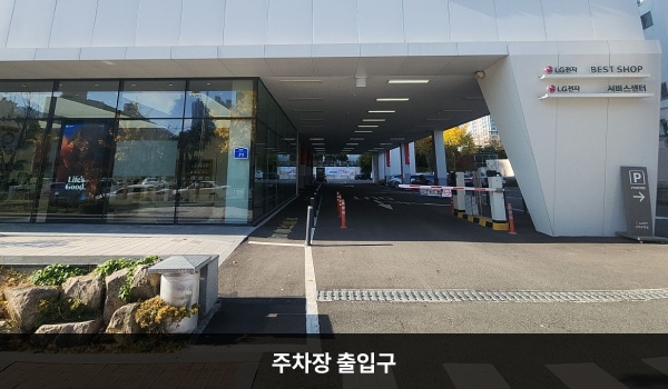 서면서비스센터의 건물 오른쪽 끝에 주차장 출입구가 있습니다. 지상 주차장 입구 앞에 'P PARKING' 안내판이 있고, 위에 'LX Z:In 인테리어' 간판이 있습니다. 오전 10시 이전에는 건물 뒤쪽 끝 철문을 이용하면 출입이 가능합니다.