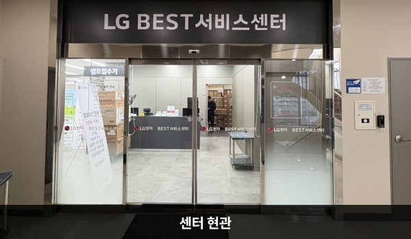 해운대서비스센터의 현관문 위쪽 큰 검은색 간판에 'LG BEST 서비스센터'라는 문구가 적혀 있습니다. 현관문은 자동문이고 들어오시면 앞에 셀프 접수기와 접수 창구가 있습니다.