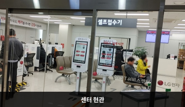 창원서비스센터의 2층 현관문 위쪽 큰 흰색 간판에 분홍색 글씨로 'LG BEST 서비스센터'라고 적혀 있습니다. 현관문은 자동문이고 오른쪽 문 중앙에 열림 버튼이 있습니다. 들어오시면 앞에 셀프 접수기가 2대 있습니다.