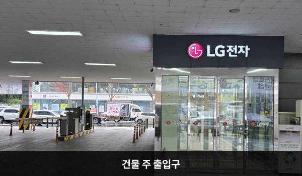전주서비스센터의 건물 주 출입구 위에 'LG전자'라는 문구가 적혀 있고, 문 앞쪽에 점자블록이 있습니다. 출입문은 자동문이며, 오른쪽 문 안쪽에 문 열림 버튼이 있습니다. 문을 열고 들어오시면 자동문이 하나 더 있습니다.