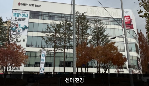 대치서비스센터의 흰색 건물에 유리창이 많습니다. 건물 꼭대기 좌측 간판에 'LG전자 BEST SHOP'이라고 쓰여 있습니다.