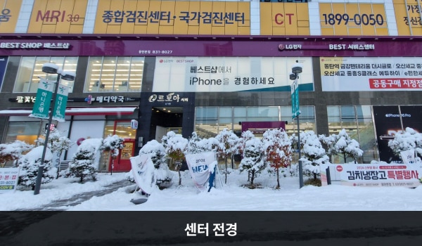 동탄서비스센터의 서비스센터는 여러 가게 간판이 많은 르보아시티 상가동 건물에 자리 잡고 있습니다. 2층 간판에 흰색 글씨, 분홍색 바탕으로 'LG전자 BEST SHOP 베스트샵', 'LG전자 BEST 서비스센터'라고 쓰여 있습니다.