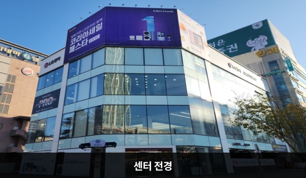 유성서비스센터의 서비스센터 건물은 유리창이 크고 많습니다. 다각형 모양의 건물 4층 붉은 간판에 'LG전자 서비스센터'라고 쓰여 있습니다.