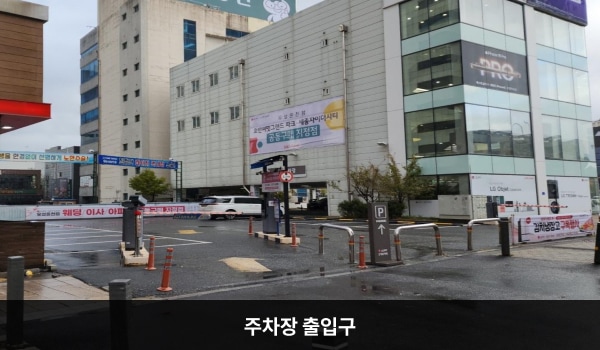 유성서비스센터의 건물 뒤편에 지상 주차장이 있습니다. 'P'라는 글자가 크게 쓰인 보라색 입간판 왼편에 있습니다.