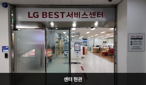 유성서비스센터의 위쪽에 'LG BEST 서비스센터'라는 문구가 적혀 있습니다. 그 아래에 유리로 된 자동문이 있습니다. 문을 열고 들어가면 앞에 셀프 접수기가 2대 있습니다.