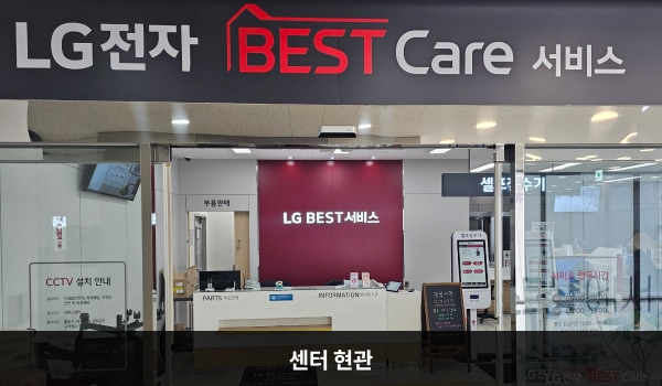 오산서비스센터의 센터 현관 위쪽에 'LG BEST Care 서비스'라는 문구가 적혀 있으며, 그 아래에 자동문이 있습니다. 문을 열고 들어가면 앞에 셀프 접수기와 안내데스크가 있습니다.