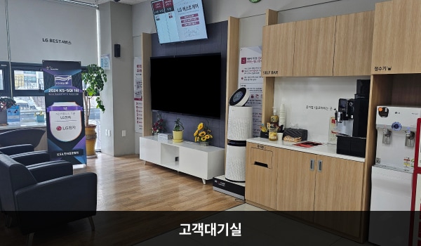 오산서비스센터의 고객대기실에는 앉아서 대기하실 수 있는 의자가 마련되어 있습니다. 대기 공간 앞쪽 벽면에는 TV와 전광판이 있고, 그 오른쪽으로 셀프바와 정수기, 휴지통이 있습니다.