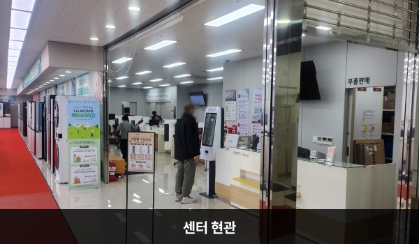동광주서비스센터의 센터 현관 앞쪽 천장에 'LG BEST 서비스센터'라는 문구가 적힌 팻말이 걸려 있습니다. 팻말 좌측에 현관문이 있습니다. 문을 열고 들어오시면 우측에 부품 판매 데스크와 셀프 접수기가 있습니다.
