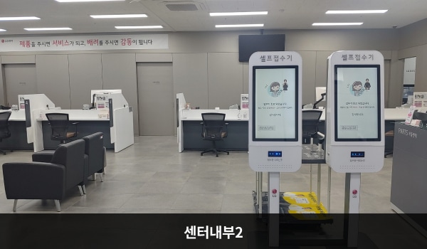 평택서비스센터의 센터 현관을 기준으로 정면에 있는 셀프 접수기 너머에는 상담 창구가 여러 개 있으며 왼쪽에 고객대기실이 있습니다.