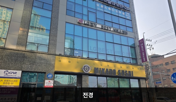 서대구서비스센터의 서비스센터 건물은 짙은 회색이며 창문이 많습니다. 건물 2층 간판에 검정색 글씨로 'LG전자 BEST 서비스센터'라고 쓰여 있습니다. 대로 앞, 건물 중앙에 건물 출입구가 있습니다.