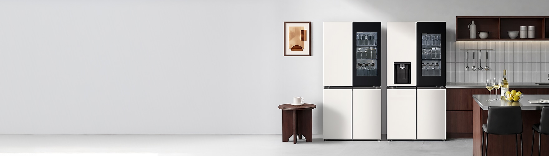 현대적인 주방 공간에 투명 유리 도어로 내부가 보이는 LG전자 STEM 냉장고 2대가 나란히 배치된 모습. 오른쪽 냉장고에는 얼음정수기가 탑재되어 있으며, 왼쪽에 원형 테이블과 액자, 오른쪽에 주방 선반과 조리대가 있음.