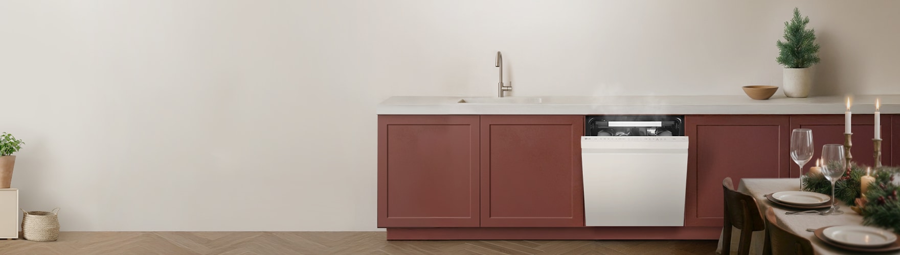 주방 하부장에 빌트인된 식기세척기가 열려 있으며 내부에서 김이 나는 모습. 주변에는 싱크대와 작은 트리 장식, 식탁 일부가 보이는 모습