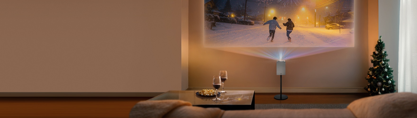 스탠드 위에 놓인 LG 시네빔 프로젝터가 거실 벽에 눈 오는 밤거리의 영화 장면을 투사하고 있습니다. 주변에는 와인 잔, 테이블, 크리스마스 트리가 배치되어 아늑한 연말 홈 시네마 분위기를 연출합니다.