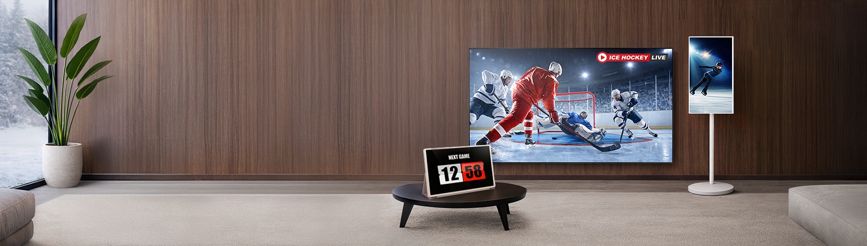 모던한 거실에 ICE HOCKEY LIVE 라고 쓰여진 문구와 아이스 하키 경기 장면의 대형 TV, NEXT GAME 12:58 라고 쓰여진 스탠바이미, 피겨 스케이팅 장면의 스탠바이미가 놓여 있다.