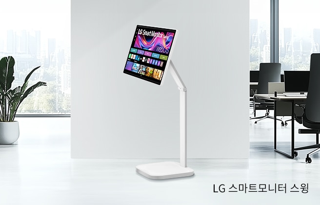 넓은 흰색 방에 서 있는 LG 스마트모니터 스윙이 있습니다. 모니터 화면에는 다채로운 그림들이 보입니다. 방 왼쪽에는 창문 앞에 화분 식물이 있고, 오른쪽에는 사무실 공간이 보입니다.이미지 하단에는 