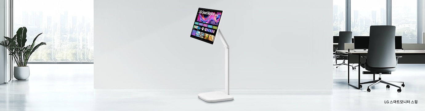 넓은 흰색 방에 서 있는 LG 스마트모니터 스윙이 있습니다. 모니터 화면에는 다채로운 그림들이 보입니다. 방 왼쪽에는 창문 앞에 화분 식물이 있고, 오른쪽에는 사무실 공간이 보입니다.이미지 하단에는 