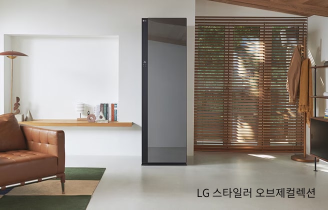 거실 공간에 의류관리기가 배치되어 있습니다. 소파, 러그, 옷걸이 등이 배치되어 있습니다.