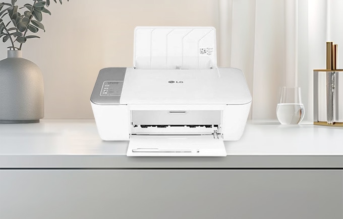 책상위에 프린터기와 화병, 물컵이 놓여있는 배너 이미지