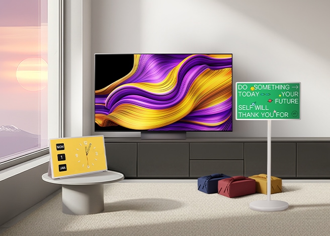 모던한 거실에 추상 무늬의 대형 TV, 노란 탁상시계, 초록색 화면의 스탠바이미가 놓여 있다.