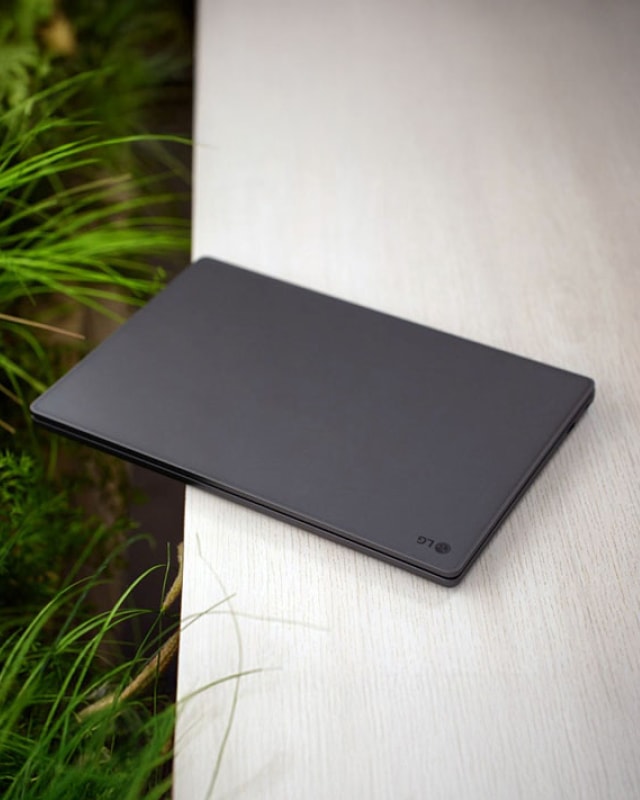 하얀 테이블에 비스듬히 놓여 있는 어두운 계열의 LG 울트라 PC