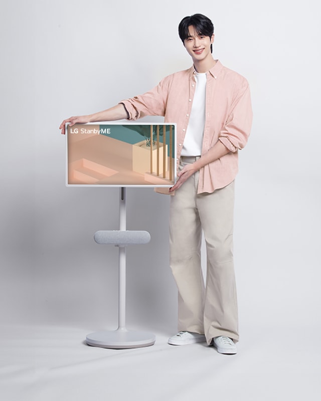 셔츠를 입은 남성이 스탠바이미 TV 옆에 서있다.