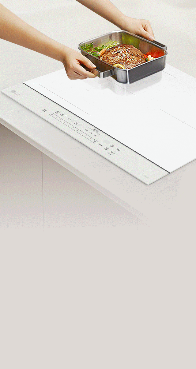 한 사람이 흰색 인덕션 위에 금속 쟁반을 올리고 있습니다. 쟁반 안에는 고기와 채소가 담겨 있습니다. 인덕션 표면에는 다양한 조작 버튼과 기능이 표시되어 있으며, '전원', '부스터', '타이머', '잠금' 등의 텍스트가 보입니다. 인덕션의 디자인은 깔끔하고 현대적입니다.